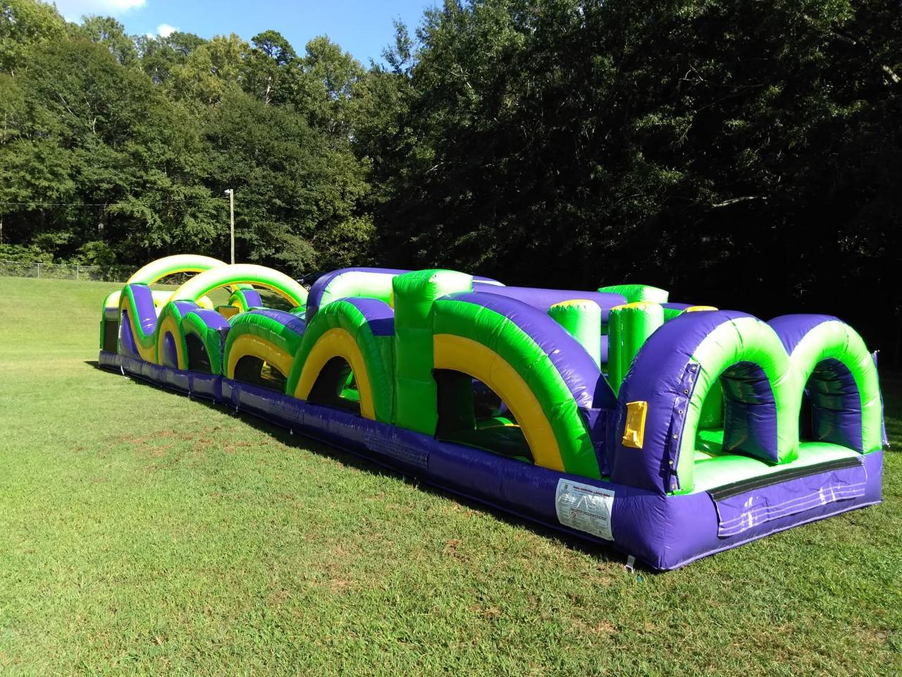 Purple, yellow, and green inflatable obstacle course with slide
